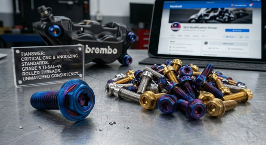 Burn Blue and gold titanium motorcycle bolts on a workbench beside a Brembo brake caliper