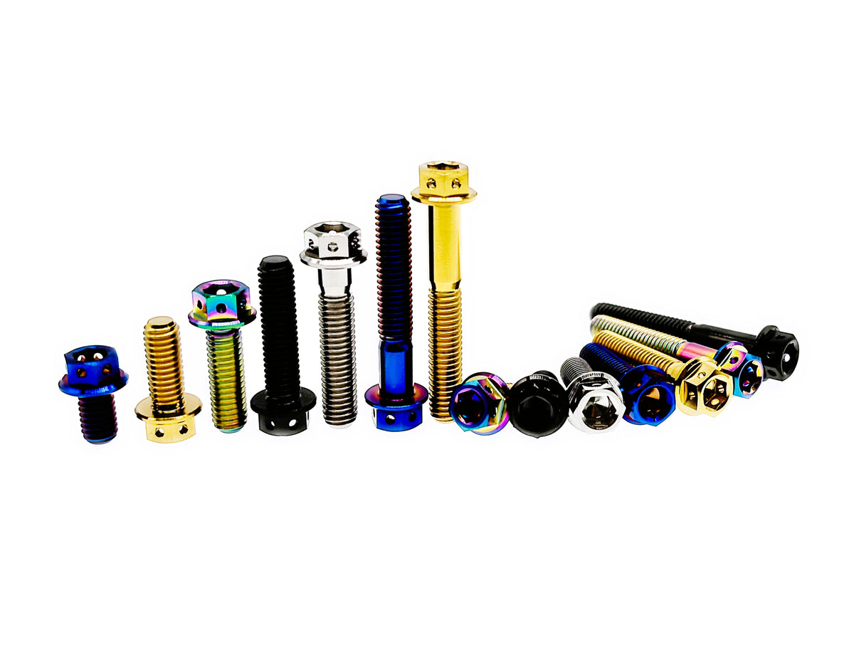 Titanium M8 flange hex bolts standing by length beside a group laid flat, five finishes